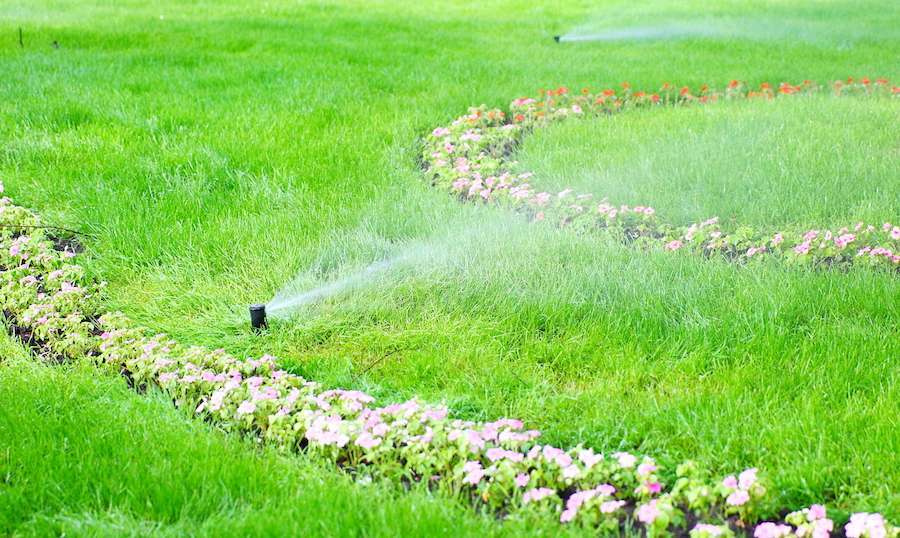 sprinkler system spraying water in green lawn